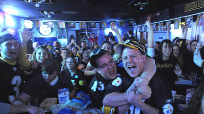 Anthony Minetola, right, of Allentown, and Rick Seyko, of Irwin, hug at the Garage Door Saloon in Oakland after James Harrison's 100-yard interception return for a touchdown at the end of the second quarter of the Super Bowl last night.