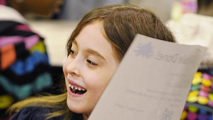 First-grader Cassidy Concanon receives a "Whale Done" award during morning assembly at Schaeffer school. She was noted by classmate Abby Fontana  for being a "good friend" and helping her with "reading and math."