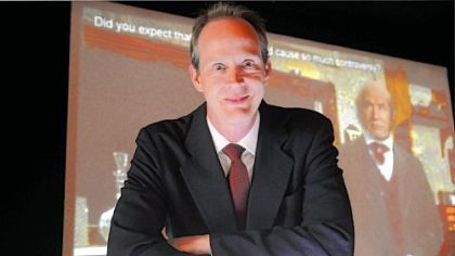 Duquesne University biologist Dr. John Pollock stands in front of the Synthetic Darwin Interview display at the Carnegie Science Center yesterday.