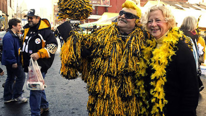 Fans, like Kate Link of Oakmont, stopped "Stanley Pompomski" to pose for photos made by friends along Penn Avenue in the Strip District today. Pompomski is a character invented by Jeff Gordon of Pittsburgh's Point Breeze neighborhood, who dresses in a suit made of black-and-gold pompoms.