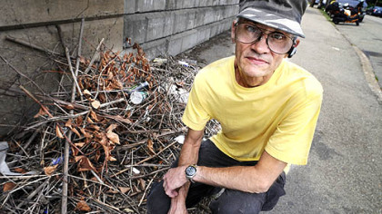 Paul McCarthy, 62, of Greenfield, next to some trash that remained after he cleaned up the hillside and sidewalk.