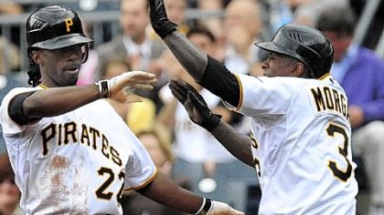 Andrew McCutchen, left, and Nyjer Morgan, right, high-five at the plate after scoring during the second inning of a baseball game against the Mets, Thursday.