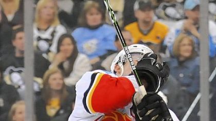 Sidney Crosby slides under the check of Calgary's Cory Sarich last night at Mellon Arena in the Penguins' 2-0 victory against the Flames.