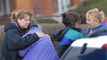 Family members of the suspect in this morning's deadly standoff offer each other comfort at the scene.