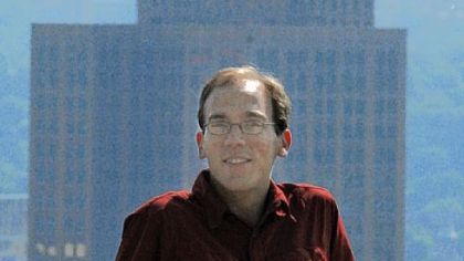 Tom Stepleton, of Squirrel Hill,  stands along Grandview Avenue on Mount Washington with the Grant Building == which is supposed to flash "PITTSBURGH" from its beacon == behind him.