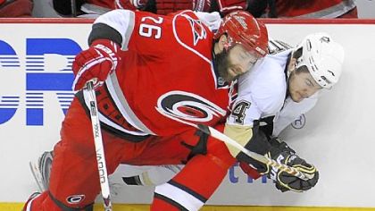 The Penguins' Chris Kunitz battles Carolina's Erik Cole for the puck along the boards last night in Game 3.