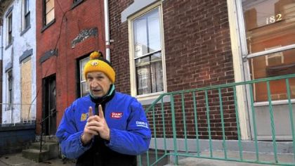 Pete Golovich in front of his home, on the right, and the connected row houses that are involved in a dispute with the water authority.