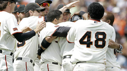Giants outfielder Randy Winn, third from right in helmet, is mobbed by his teammates after hitting an RBI single down the first base line with two outs in the 10th inning.