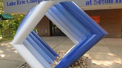 Abstract sculpture "Pipe Theme in Red Orange" by Josefa Filkosky is now blue in its site in front of Lynch Hall at Seton Hill University.