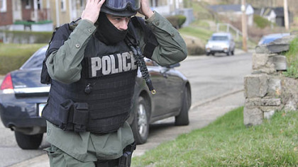 An officer dons his gear as police respond after a man involved in a domestic dispute opened fire on police today Stanton Heights, killing three officers and injuring two others.