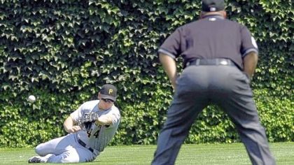 Pirates right fielder Brandon Moss is unable to catch a line drive triple by Chicago Cubs' Sam Fuld as second base umpire Eric Cooper watches during the first inning of yesterday's game in Chicago.