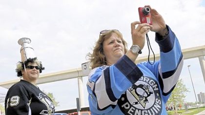 Elaine Anderson, of Ross Township, takes a photo of the Penguins' team bus arriving at Joe Louis Arena in Detroit yesterday.  At left is her friend, Christine Szymarek, of White Oak.