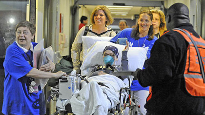 First patient to make the move waves to bystanders while being transported from Oakland to the Children's Hospital new location in Lawrenceville this morning.