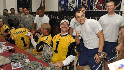 Bill Cowher, the former head coach of the Pittsburgh Steelers, poses with U.S. Air Force SRA Jonathan Echevarria at Forward Operating Base Warrior near Kirkuk, Iraq, Thursday. Echevarria is flashing Cowher's Super Bowl ring at a USO appearance at Forward Operating Base Warrior near Kirkuk, Iraq, Thursday. Cowher is one of a team of NFL coaches, wearing the colors of the U.S. Army's First Cavalry Division from Fort Hood, Texas, are part of a week-long USO tour to bring troops a touch of home during the July 4th holiday.