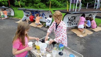 Art teacher Mary Jane Hadley, center, supervises paint distribution as her fourth-grade art students at Rowan Elementary School put the final touches on their class project, painting three Cranberry snowplow blades with designs voted on by students at the school. Rowan Elementary is in the Seneca Valley School District.