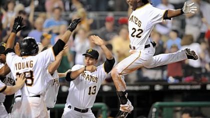 Pirates' Andrew McCutchen leaps into his awaiting teammates after scoring the game-winning run against the Phillies at PNC Park tonight.