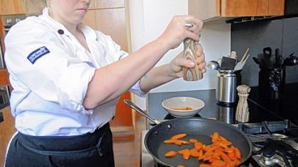 Chef Rachel Lori seasons fresh sliced carrots with salt and pepper as she sautes them in oil.