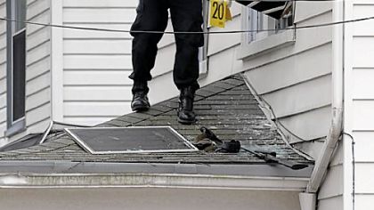 Trooper Brian Kendgia, an investigator with the State Police Forensic Services Unit, gathers evidence at the scene of a shootout on Concord Avenue in Greensburg early yesterday.