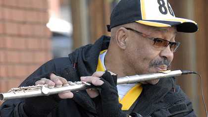 Street musician Ali Param of Swissvale plays the Steeler "Here We Go" fight song on his amplified flute for visitors to Pittsburgh's Strip District where a throng of Steeler fans mingled on blocked-off Penn Avenue today, soaking up the winter sunshine and enjoying pregame revelry before Super Bowl XLIII.
