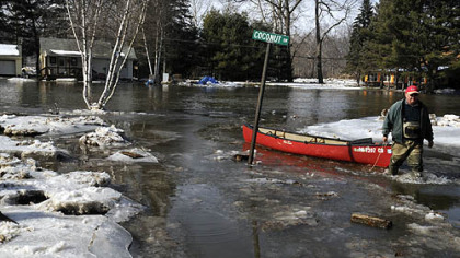 Dave Porada pulls his canoe across Neshannock Creek near a flooded Coconut Drive. His house is to the left, where he has lived since the mid-1970s. He said, "You lie in a river valley -- you live with it or you leave." Mr. Porada said about 12 or 13 houses were affected by the dam of ice, but only six houses have year-round residents. He said his basement is completely flooded.