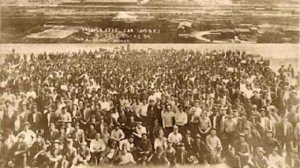 In the foreground, striking workers assemble in McKees Rocks. In the background is the Pressed Steel Car Co. plant.