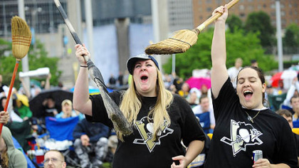 The sweep is on ... Geralyn Holby of Irwin, left, and Nicole Agulia, right, hold their brooms and cheer the Penguins in game 4 against Carolina at the Jumbotron at the Mellon Arena Tuesday night.
