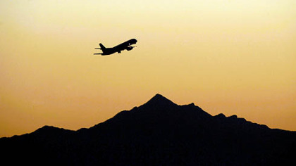 An airplane takes off at sunset from Sky Harbor International Airport, in Phoenix. The number of vacationing Americans will be down this summer, according to a new AP-Gfk Poll.