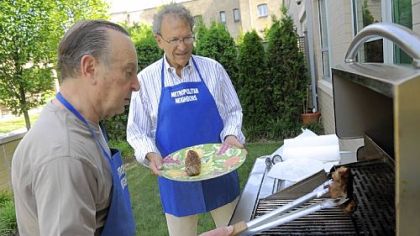 Joe Massaro, left, and Charles Miller grill pork tenderloins while helping to prepare a dinner for residents at the Family House Neville, temporary home to
