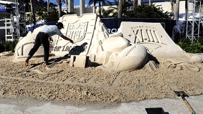 Mark Mason of Team Sandtastic puts the finishing touches on a sand sculpture at the NFL On Location Beach House outside the entrance to Raymond James Stadium yesterday in Tampa, Fla.