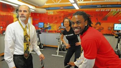 Jay Hope, left, associate executive director of the Penn Hills YMCA, and fitness coach Lomel Patterson, right, demonstrate an interactive snowboarding video game in the new XRKade at the Penn Hills YMCA on Friday. In the background is  XRKade director Andrea Oh. The XRKade, a new facility at the Penn Hills YMCA, uses video games to attract  children 9-12 to physical activity.