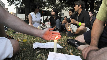 Friends Josh Clary of Greenfield, left, and Mehrdad Emamzadeh, right, who was born in America after his Iranian parents immigrated, join about 60 others in a candlelight vigil in Market Square in support of the protesters in Iran.