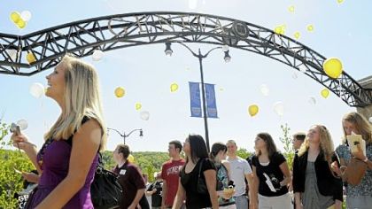 Graduating seniors at Geneva College release balloons while walking through the brand-new arch at the campus entrance.