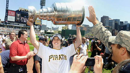 Sidney Crosby hoists the Stanley Cup while wearing a Pirates jersey as members of the Stanley Cup champion Pittsburgh Penguins attend a baseball game between the Pittsburgh Pirates and the Detroit Tigers.