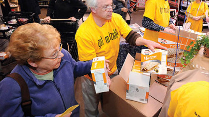 Irv Younger, center, of Or L'Simcha, and Joe Jolson, right, of Beth Shalom Congregation, restock free matzo samples as fast as shoppers snapped them up at the Giant Eagle Market District store yesterday in Shadyside.