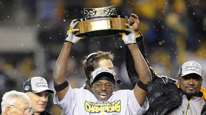 Dan Rooney and his son Art look on as Santonio Holmes and Mike Tomlin hoist the AFC championship trophy after defeating the Ravens yesterday at Heinz Field.