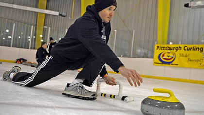Jerrett Covington, 30, of Moon, delivers the stone during a "learn to curl" class at the Robert Morris University Island Sports Center on Neville Island.
