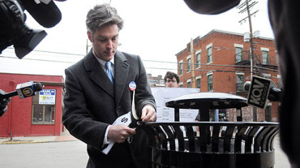 City Councilman Patrick Dowd ties a $1,010 price tag onto a city garbage can along Carson Street on the South Side yesterday.