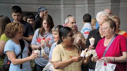 A group of people gather for the candlelight vigil outside the City-County building Downtown yesterday.