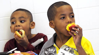 Angel Butler, left, and Zyier Gibson, first-graders at Pittsburgh Sunnyside Elementary and Middle School in Stanton Heights have turkey hot dogs on whole wheat buns and locally grown peaches for lunch.