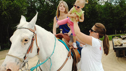 Bethann Palone lifts the littlest Palone (for now), 2-year-old Alana into the saddle with Hannah.