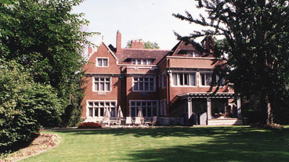 The large lawn behind the mansion includes a flagstone patio, a red brick path and lots of mature trees.