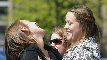Geneva College graduating seniors, from left, Toni Marshall, Meaghan Rouzer and Robyn Weber, share a moment after walking through the new arch at the campus entrance.