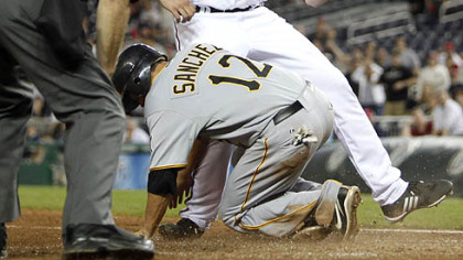 Home plate umpire Ed Rapuano, left, watches as  Freddy Sanchez slides under Washington Nationals' pitcher Joel Hanrahan to score the go-ahead run on a wild pitch during the ninth inning of last night's baseball game in Washington.