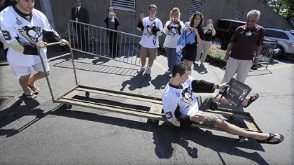 Bill Guerin, the oldest Penguin, is carted out of Mellon Arena yesterday by Kris Letang before the parade.