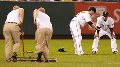 Pirates third baseman Andy Laroche warms up with outfielder Delwyn Young as the grounds crew prepares the field.