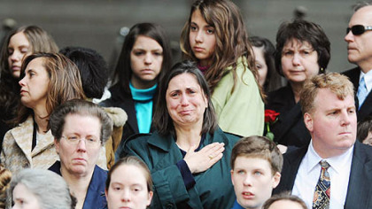 Friends and family of slain officers Paul J. Sciullo II, Eric G. Kelly and Stephen J. Mayhle watch as the officers' caskets are carried into the City-County Building yesterday.