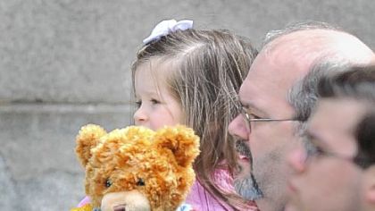 Her police teddy bear in hand, a girl waits to see the caskets of the slain police officers.