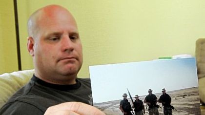 Former West Virginia National Guardsman Russell Powell holds a photo of him on patrol near a water treatment plant in Basrah, Iraq, in 2003. where he was likely exposed to hexavalent chromium, a toxic chemical.