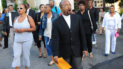 The Rev. David Thornton, center, pastor of Grace Memorial United Presbyterian Church, signs hymns while leading members of the congregation and members of Pittsburgh government on a tour up Iowa Street in the Upper Hill District, where stop signs and repairs are needed.