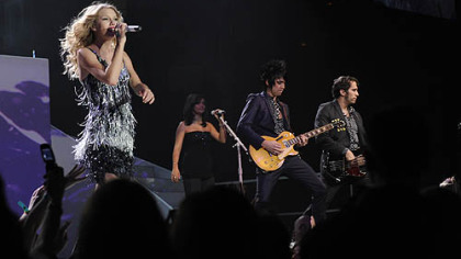 Taylor Swift with the band in the background.